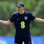 Thomas Tuchel en costume, souriant, lors d'une conférence de presse.