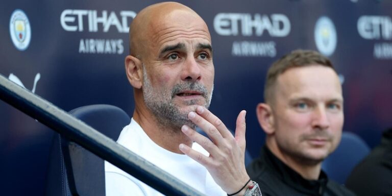 Pep Guardiola pointant du doigt sur le banc de l'Italie, avec le logo de la FIGC en arriere-plan.